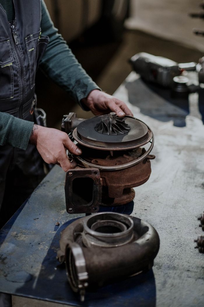 services-03 Mechanic working on a turbocharger assembly in a repair shop setting.